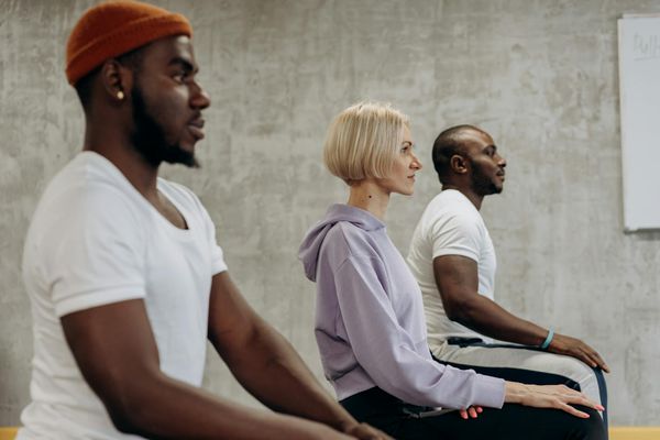 Diverse group of people sitting on yoga mats in a circle.
